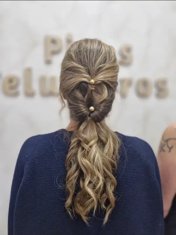 Coleta trenzada con ondas, vista de espaldas frente al rótulo de la peluquería