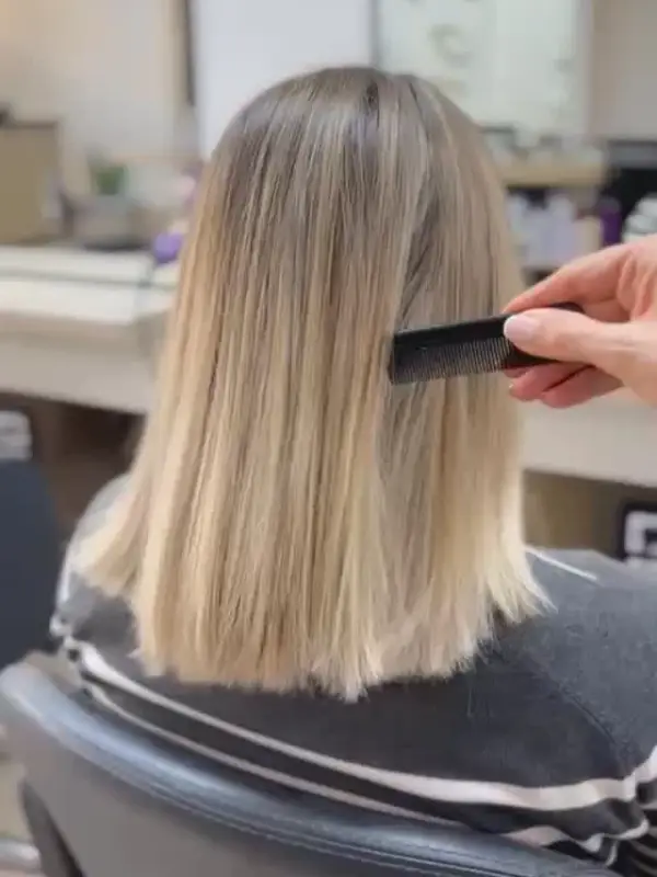 Media melena rubia lisa, vista de espaldas mientras se peina