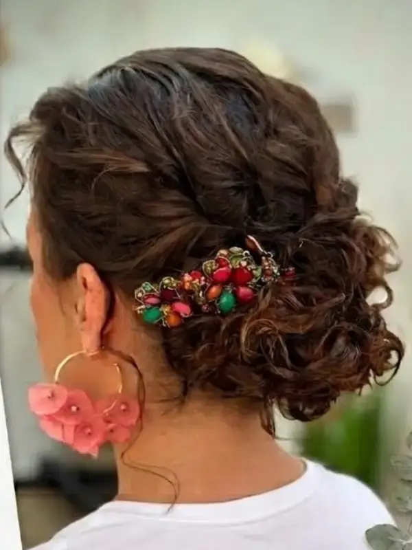 Recogido bajo con rizos y un adorno de flores rojas, visto de lado y de espaldas